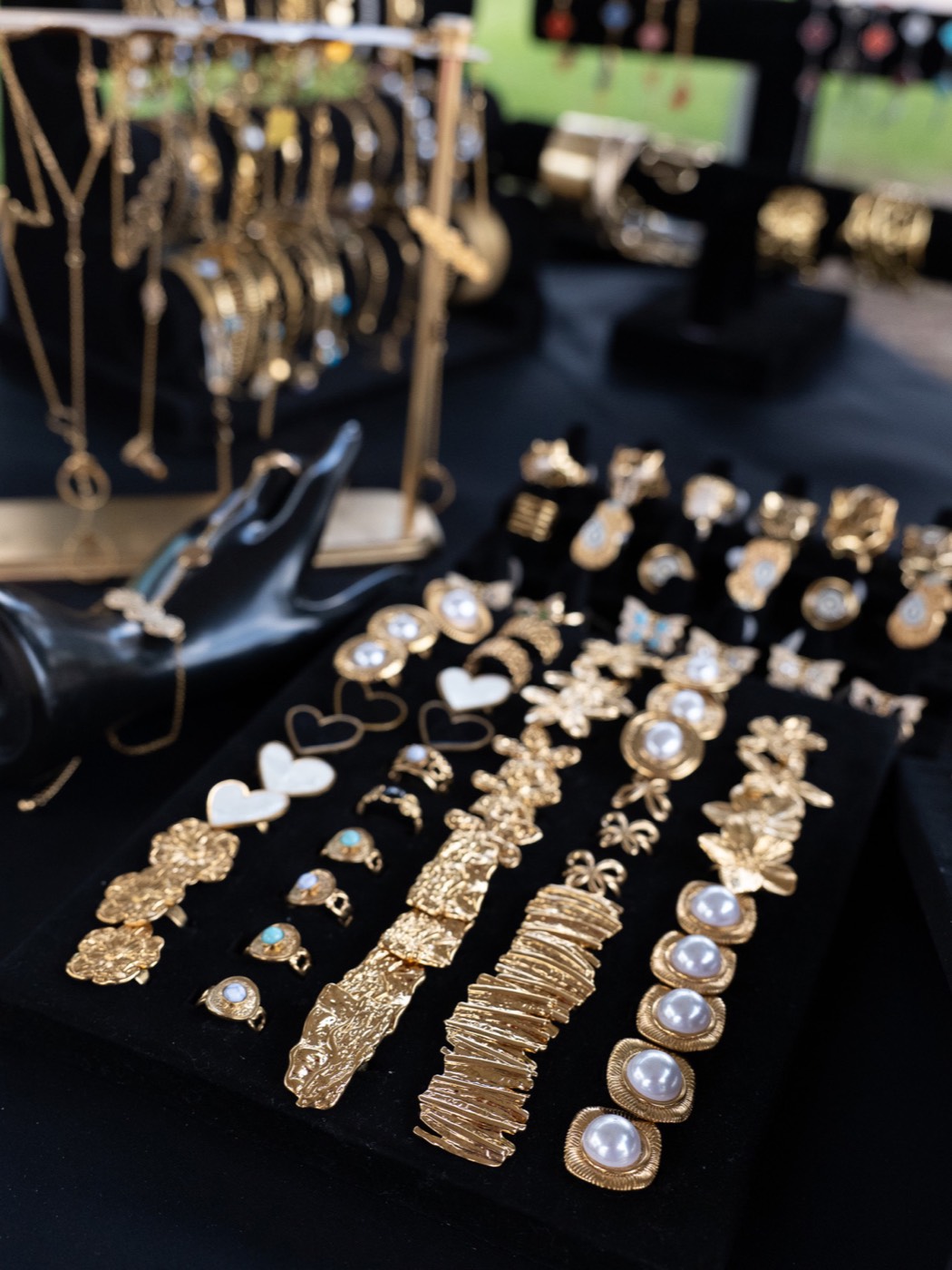 Handmade gold jewellery and pearl earrings laid out on black velvet